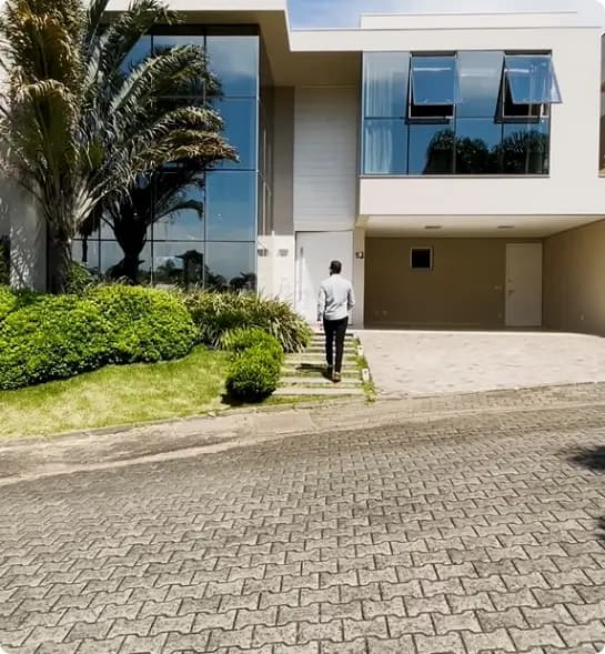 Gabriel Leão de costas para foto, de frente para uma casa